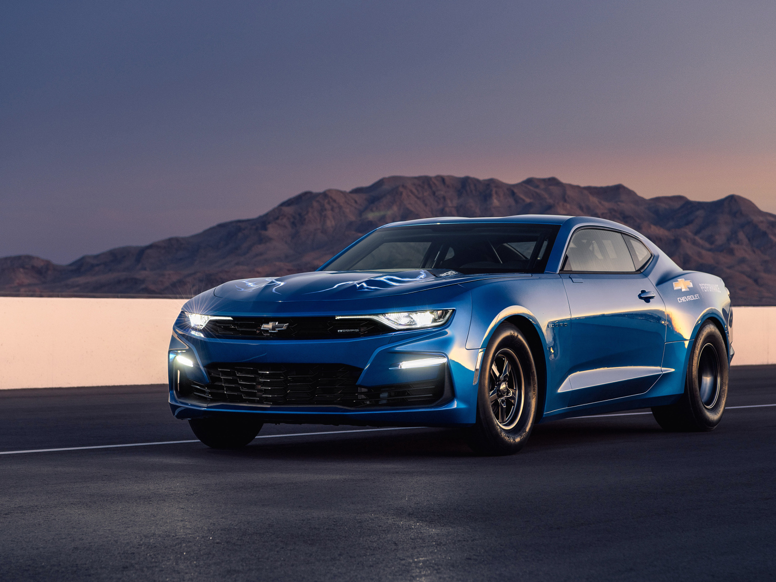 Синий автомобиль Chevrolet Camaro на трассе на фоне гор