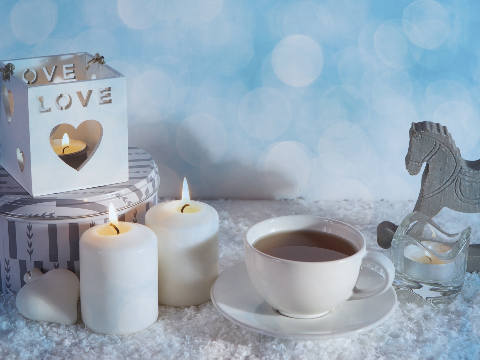 Свечи, чашка чая и фигура лошади на столе 