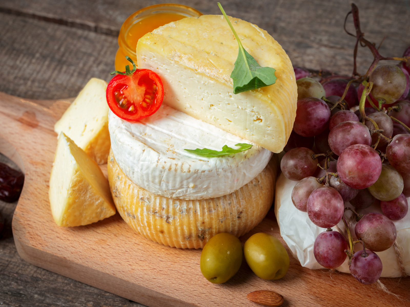Сыр на разделочной доске с виноградом и оливками