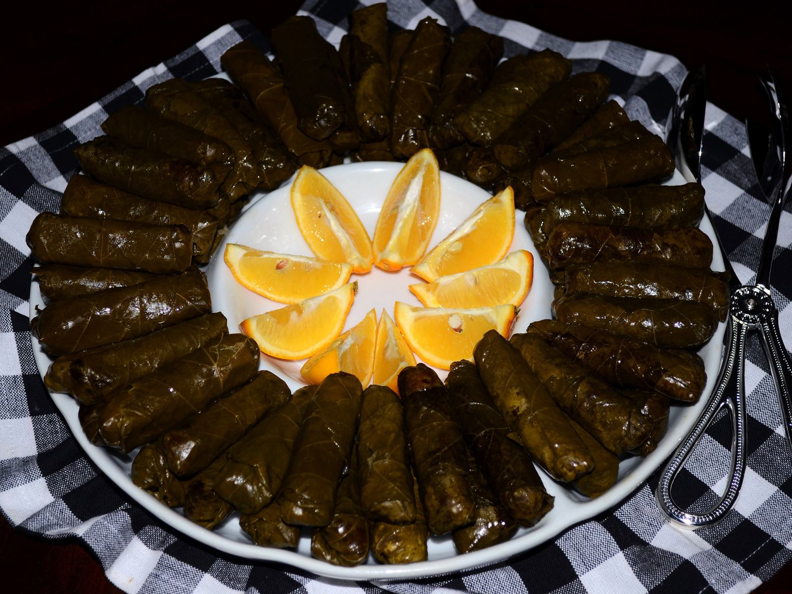 Долма на большом блюде с кусочками апельсина 