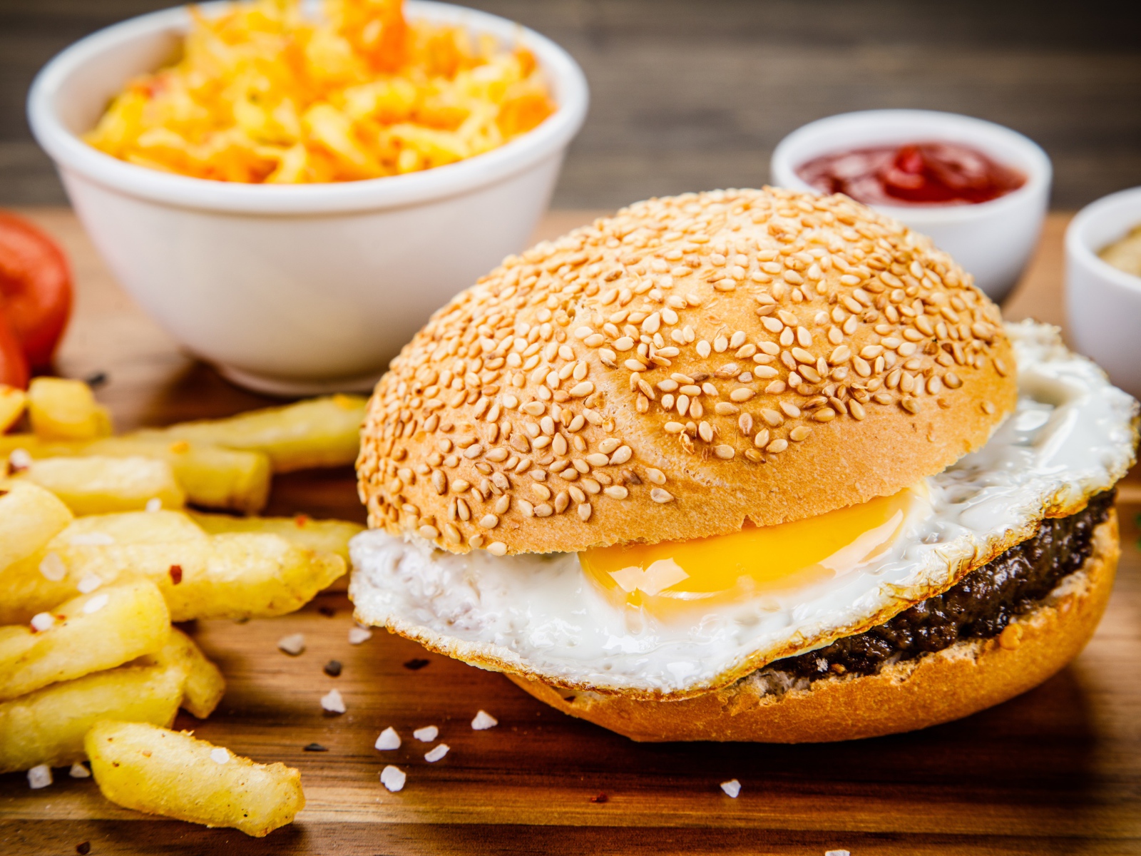 Гамбургер с яичницей на столе с картофелем фри и соусом