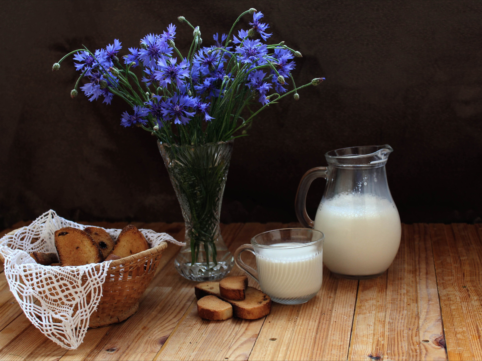 Молоко с сухариками на столе с букетом синих васильков