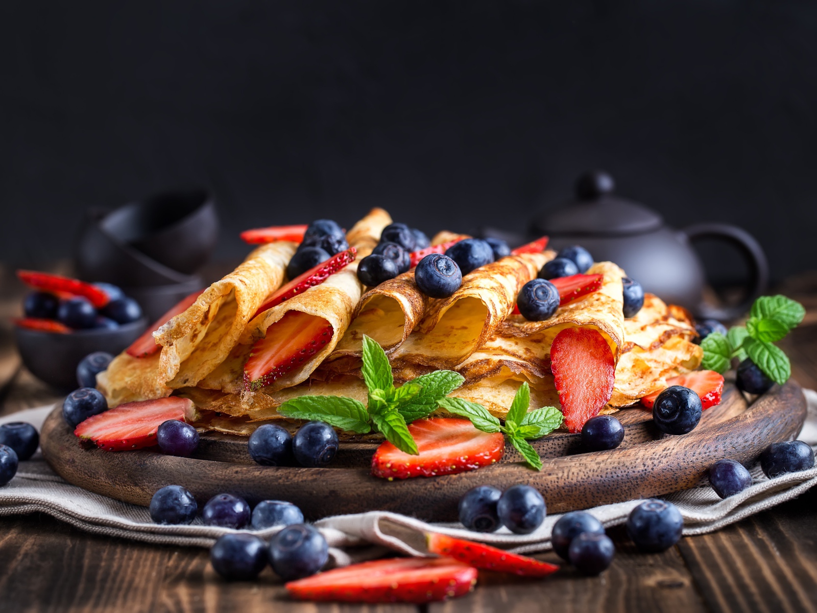 Блинчики с ягодами черники и клубники на столе