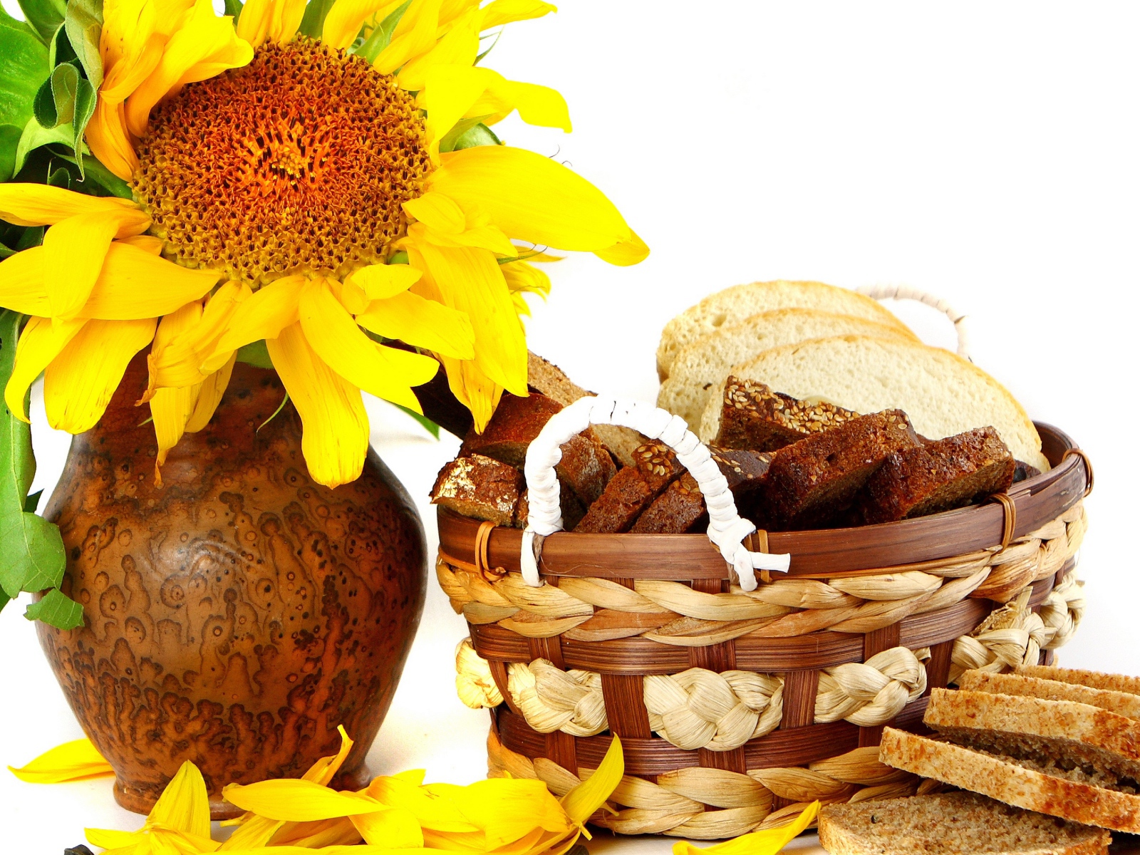 Цветок подсолнуха в кувшине на столе с корзиной с хлебом на белом фоне