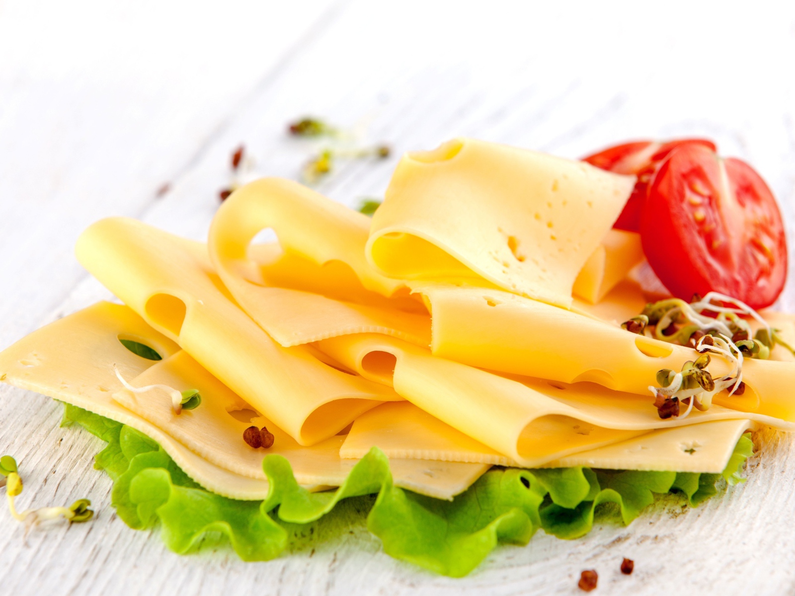 Тонко нарезанный сыр с листом салата и помидором