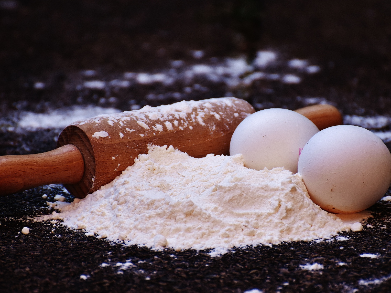 Два яйца, мука и скалка на столе