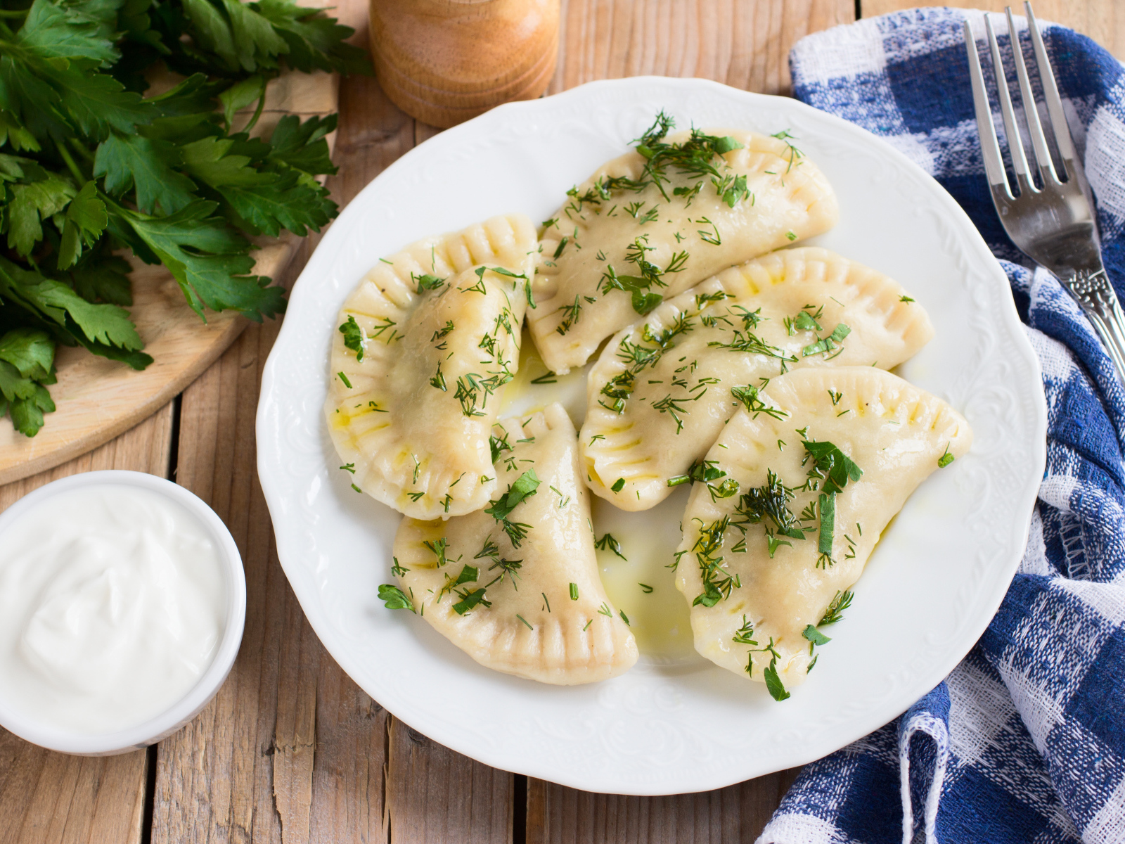 Вареники с зеленью на белой тарелке 
