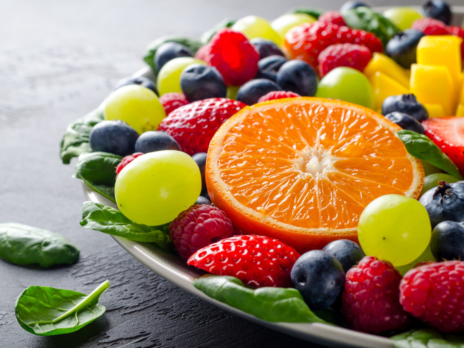 Аппетитные ягоды на тарелке с зелеными листьями базилика