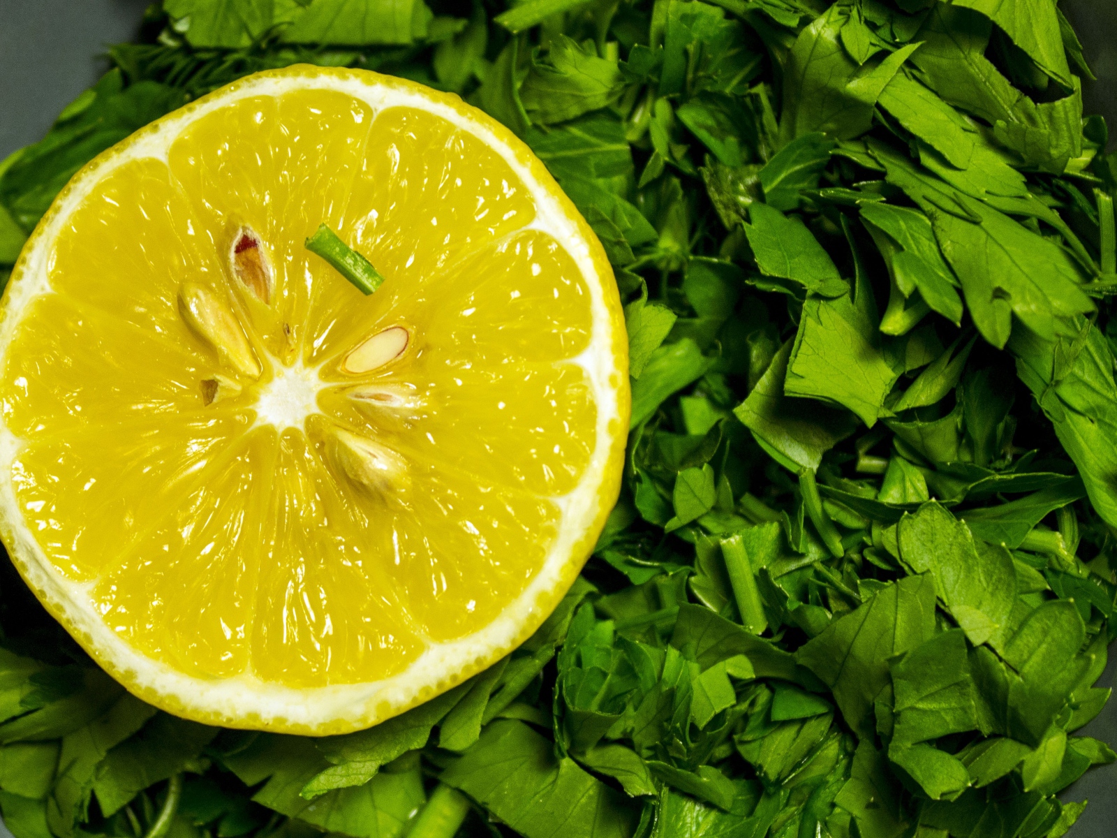 Половина желтого лимона с нарезанной зеленью петрушки 