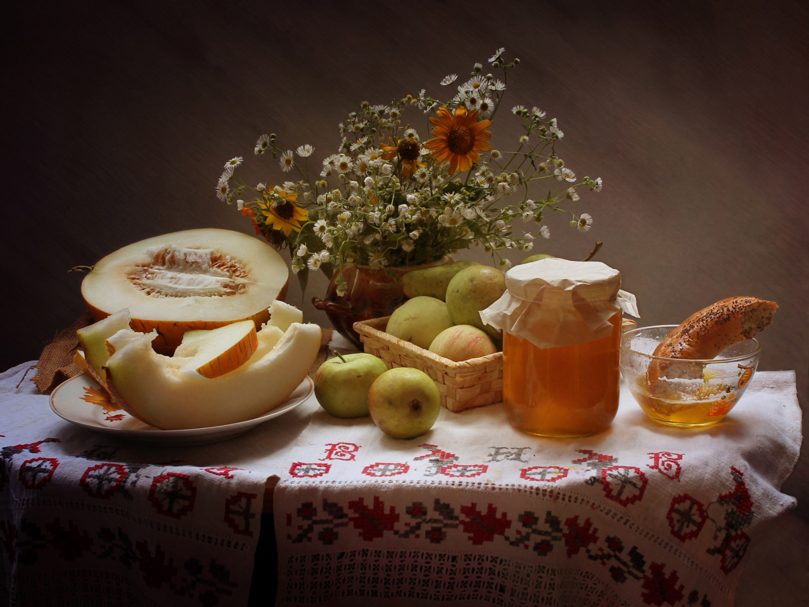 Сочная дыня с яблоками на столе с медом и букетом цветов