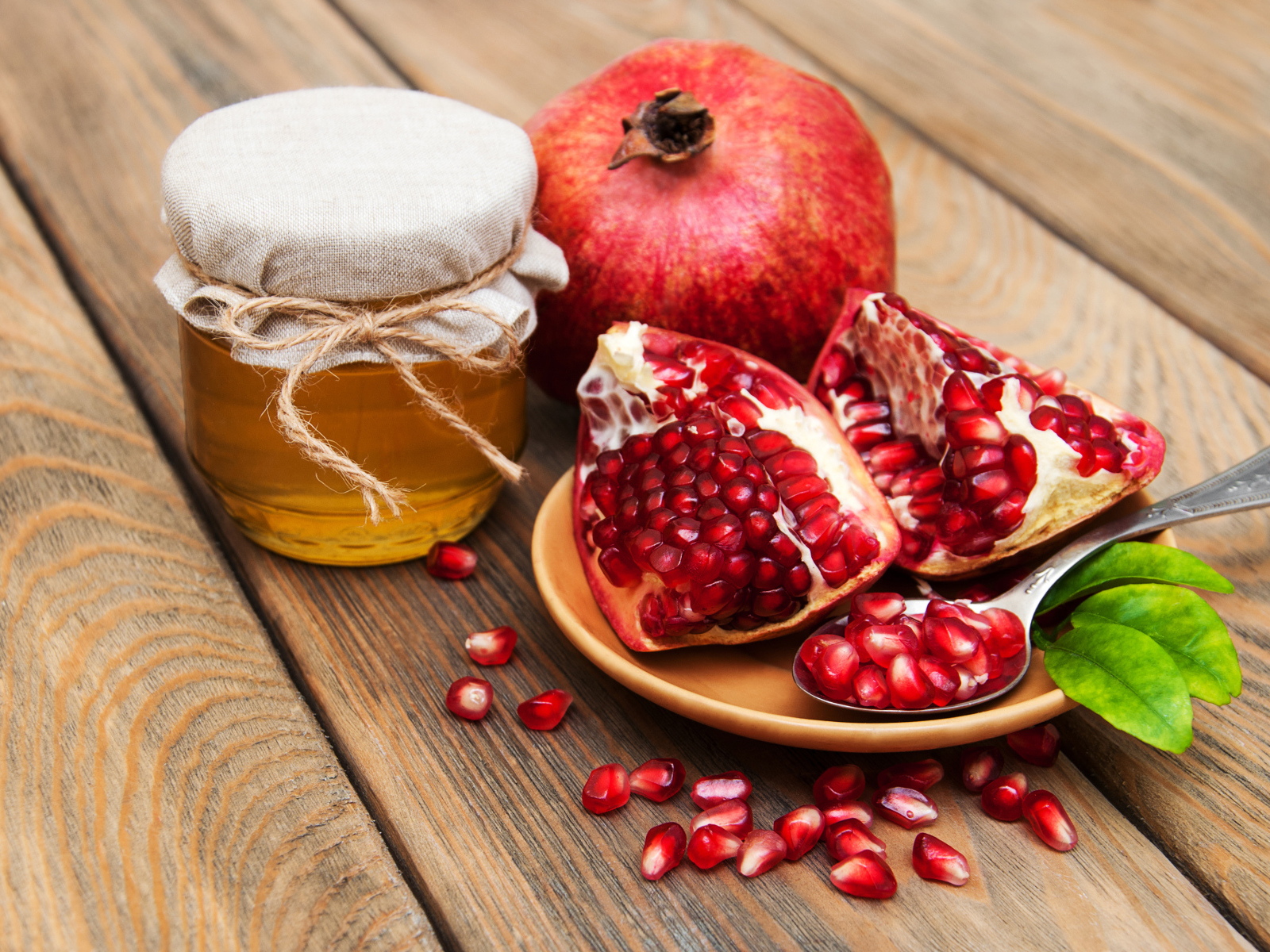 Гранат на деревянном столе с банкой меда