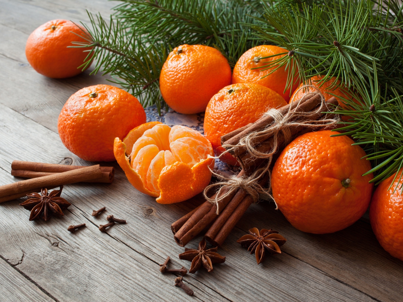 Вкусные спелые мандарины с корицей и бадьяном на столе с еловой веткой