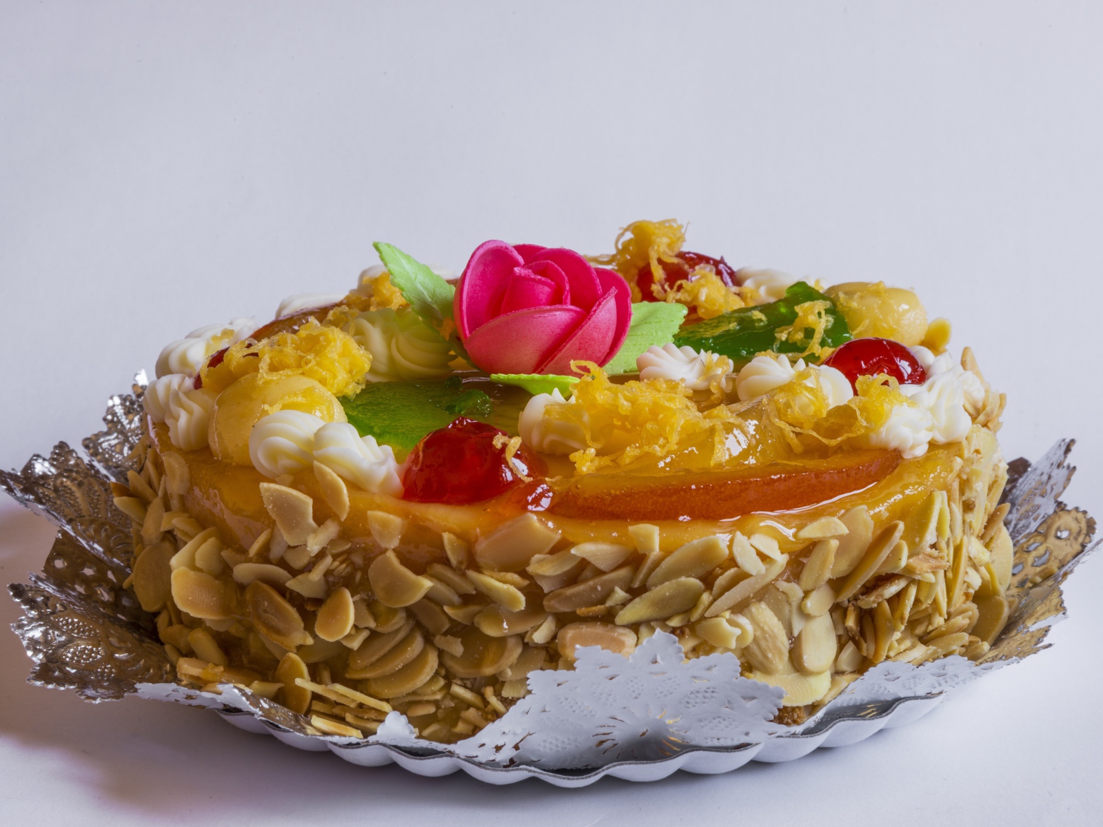 Красивый торт с кремом и ягодами украшен розовым цветком