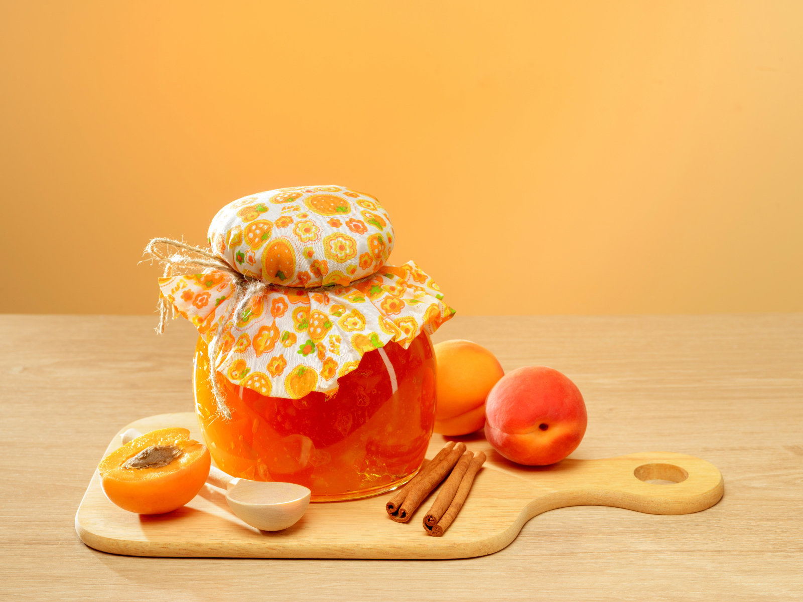 Банка абрикосового джема на столе с фруктами