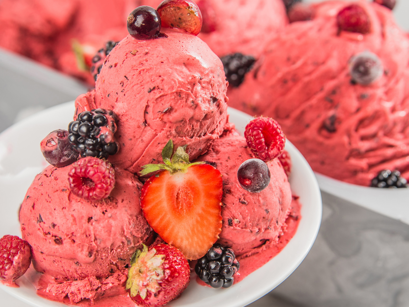 Шарики мороженого с ягодами на белой тарелке