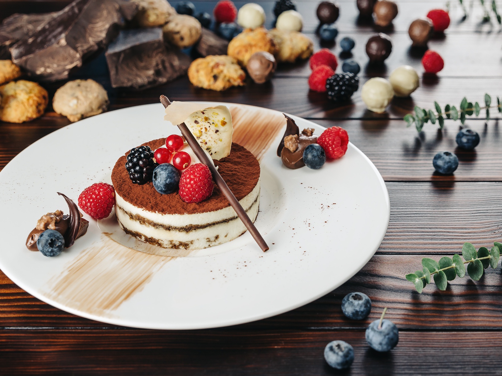 Пирожное с ягодами и шоколадом на белой тарелке 