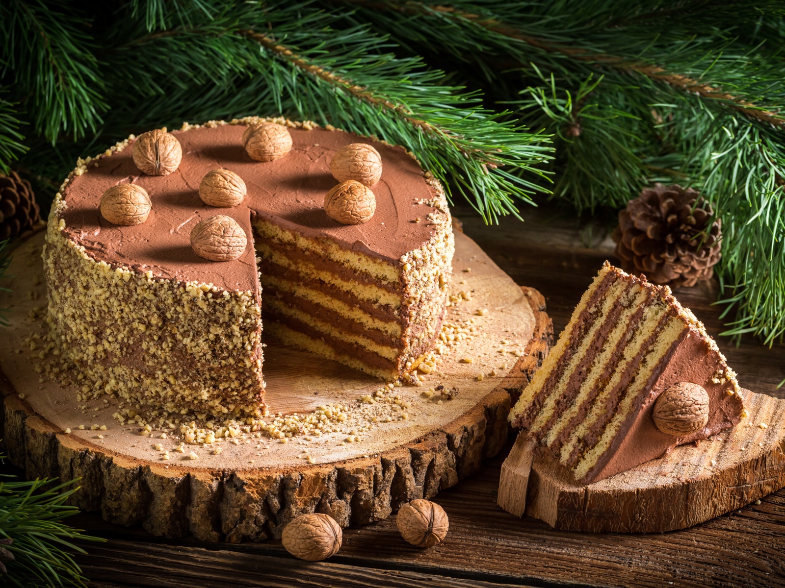 Торт с шоколадом и орехами на столе с еловой веткой