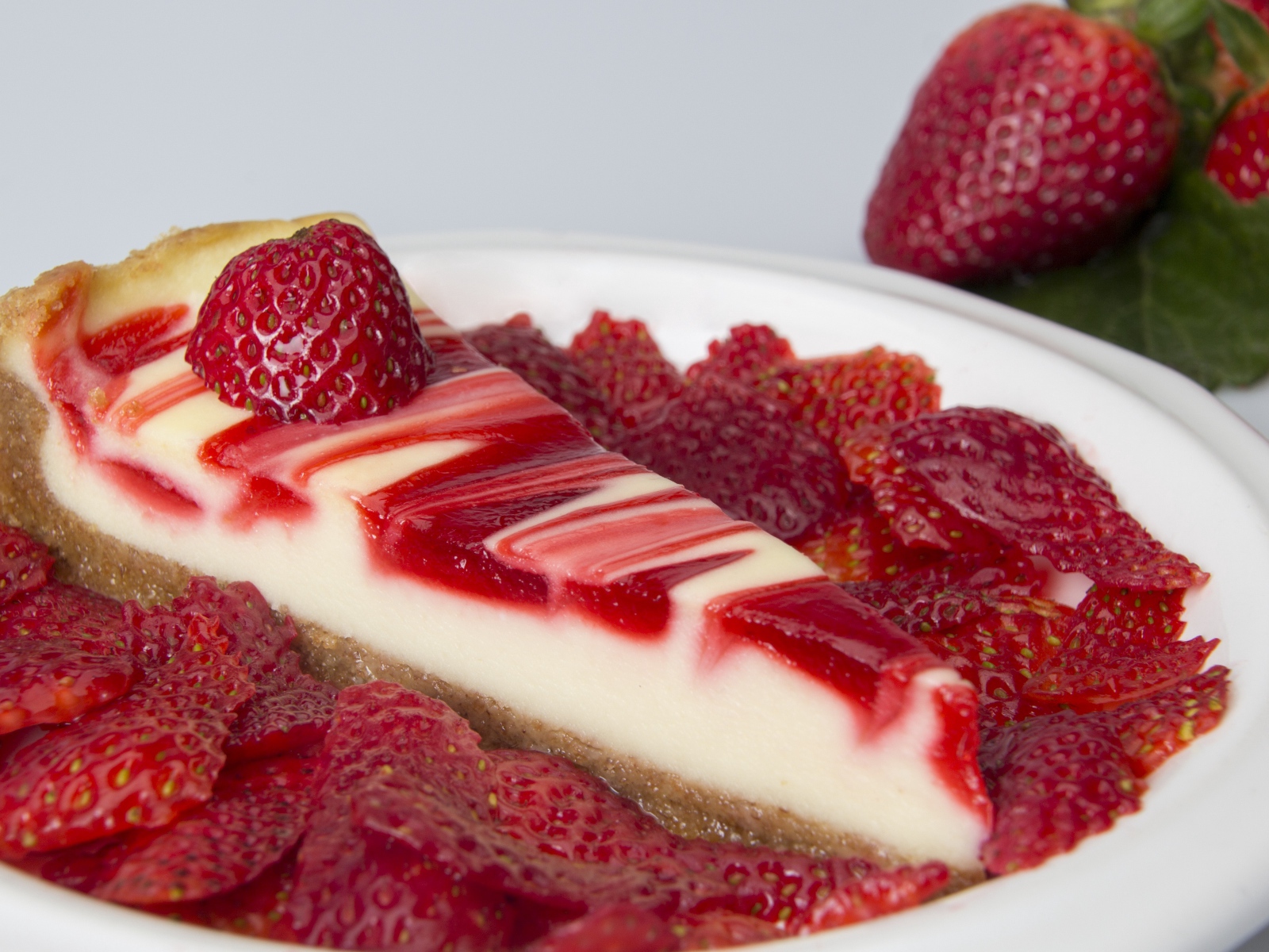 Чизкейк с ягодами клубники в белой тарелке 