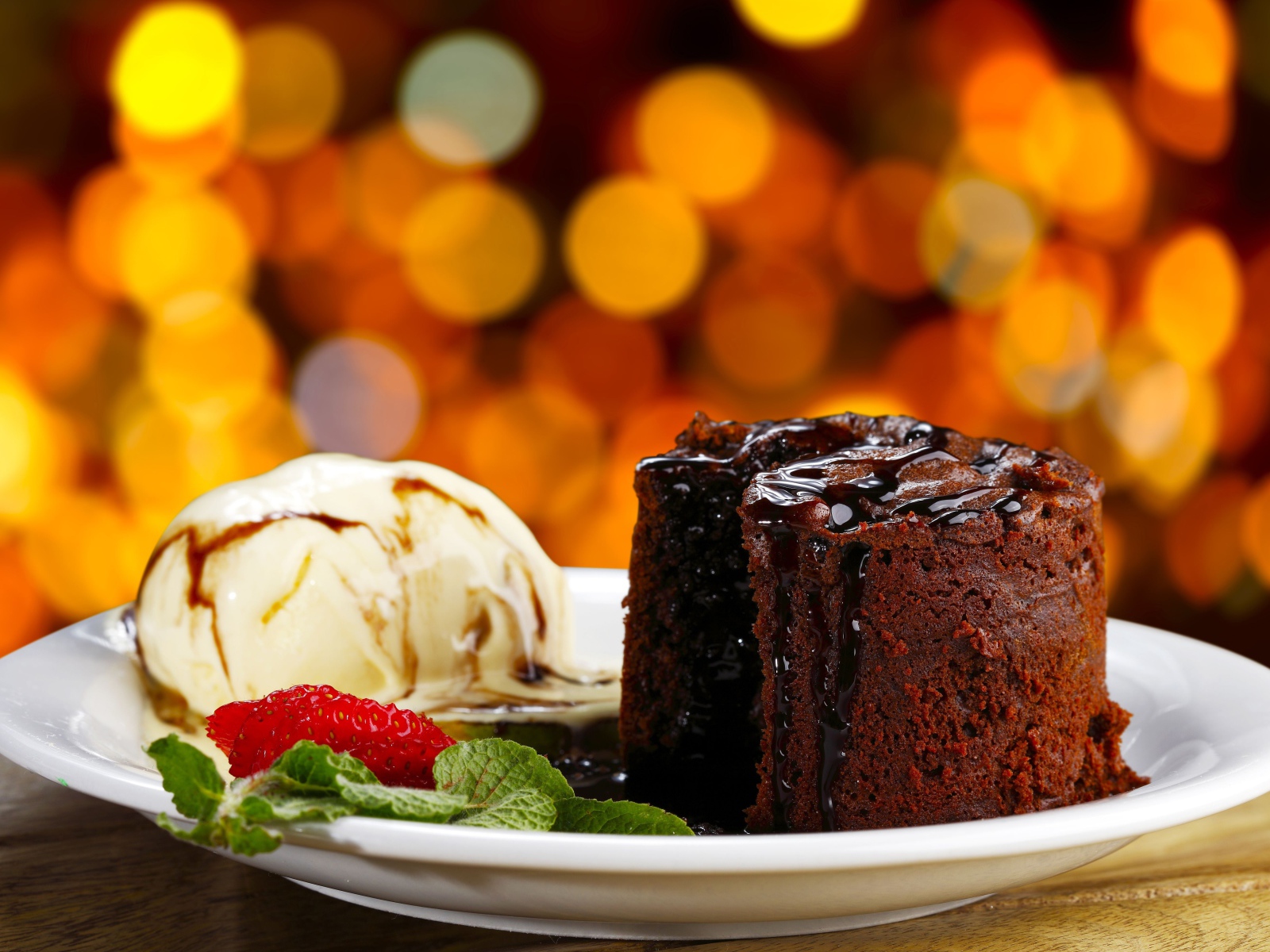 Шоколадное пирожное с мороженым и клубникой на тарелке