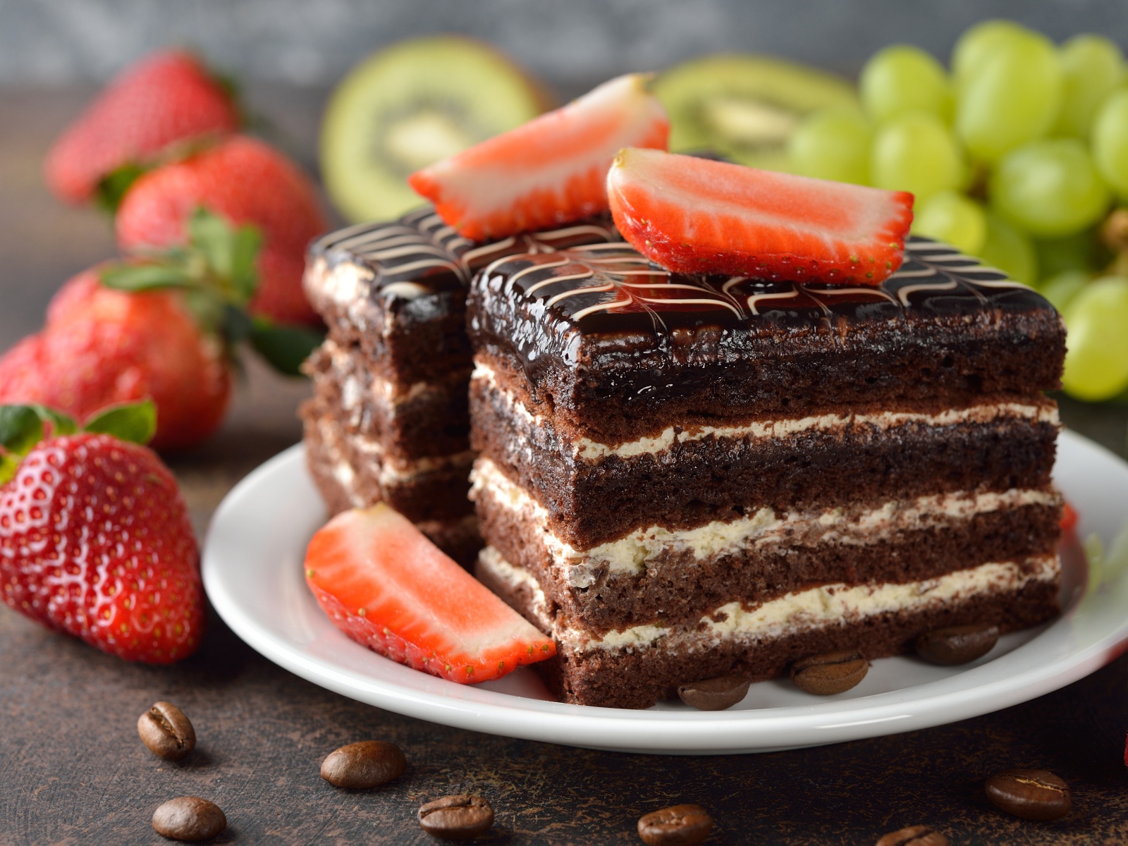 Шоколадное пирожное с клубникой и виноградом на столе