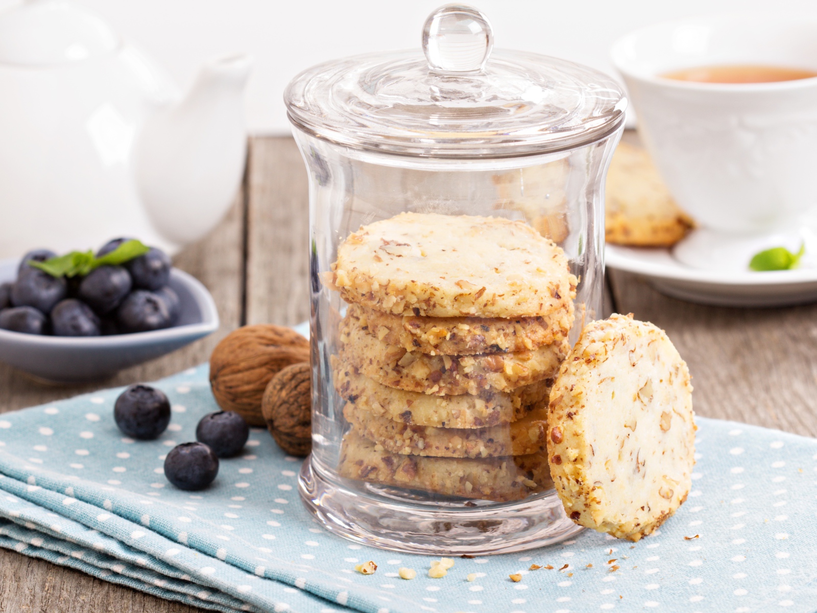 Печенье в стеклянной банке на столе с орехами и черникой