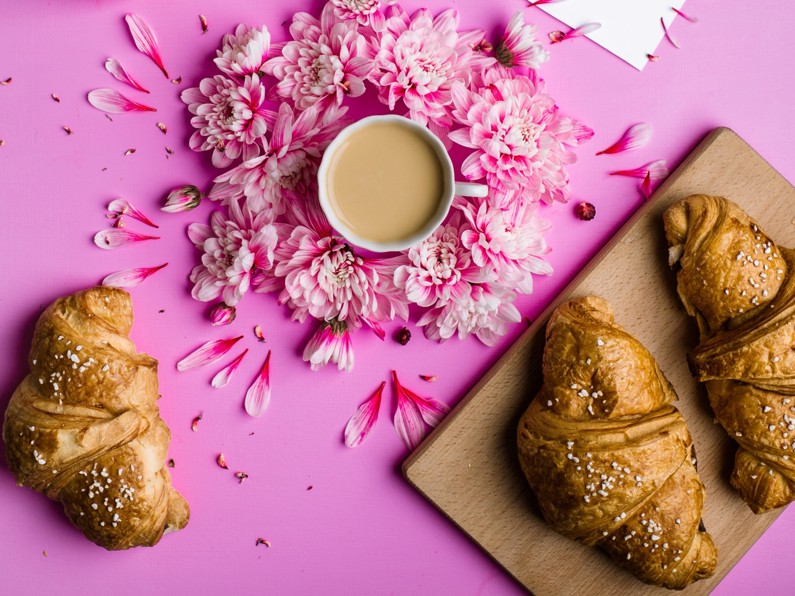 Свежие круассаны на столе с чашкой какао и цветами хризантемы