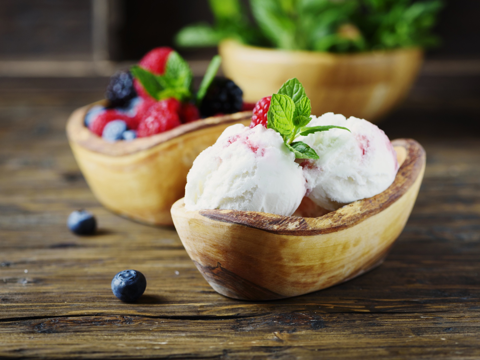 Шарики мороженого с ягодами в деревянной посуде