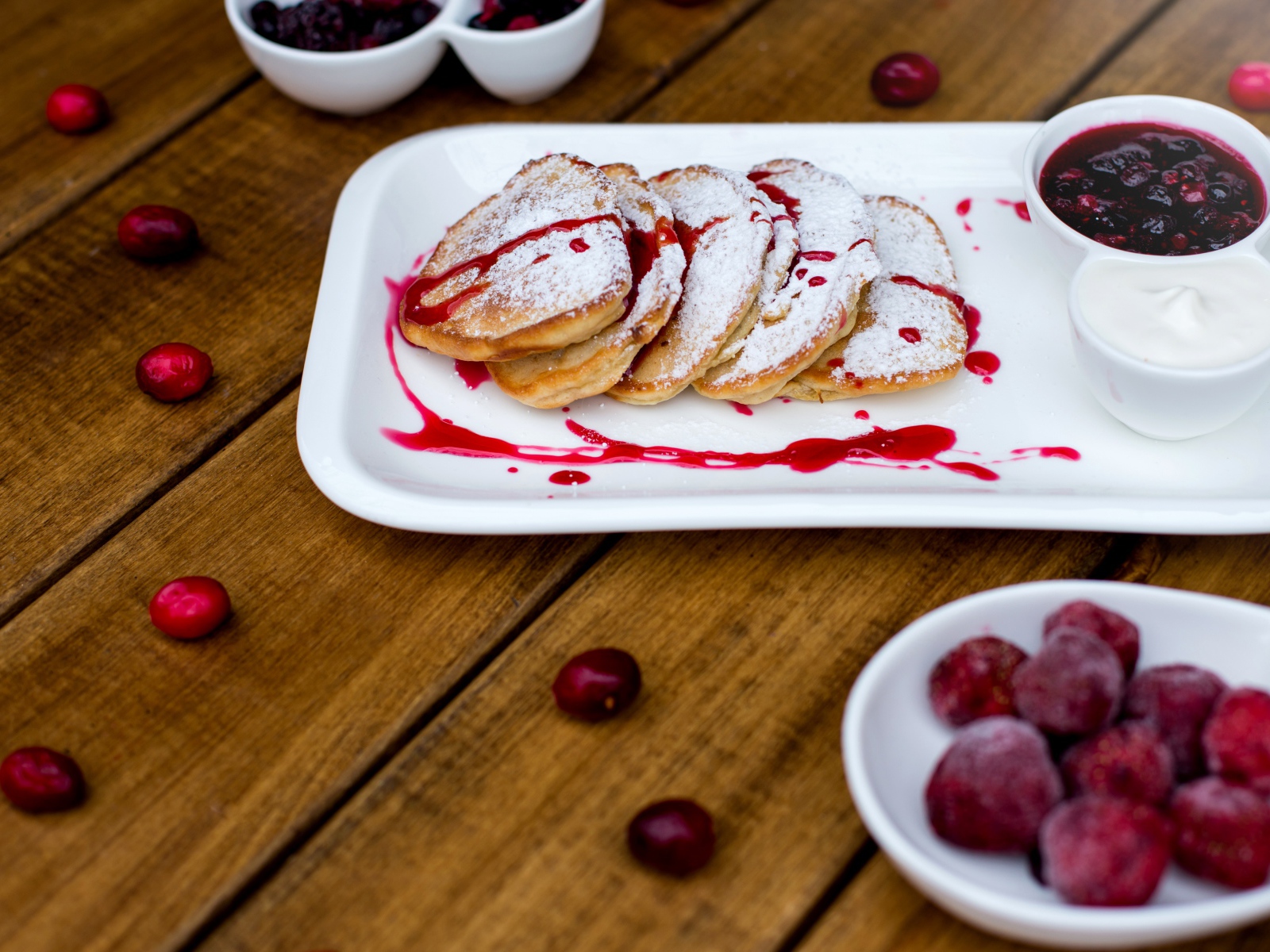 Оладьи с сахарной пудрой и вареньем на белой тарелке