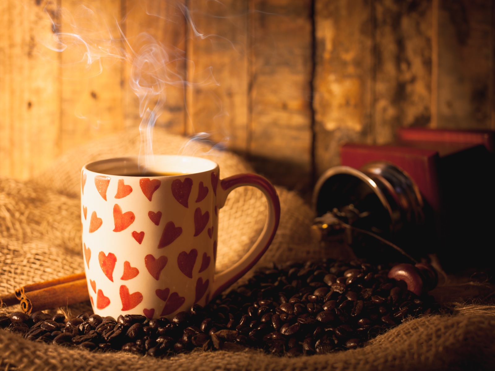 Чашка с горячим кофе на столе с кофейными зернами и корицей