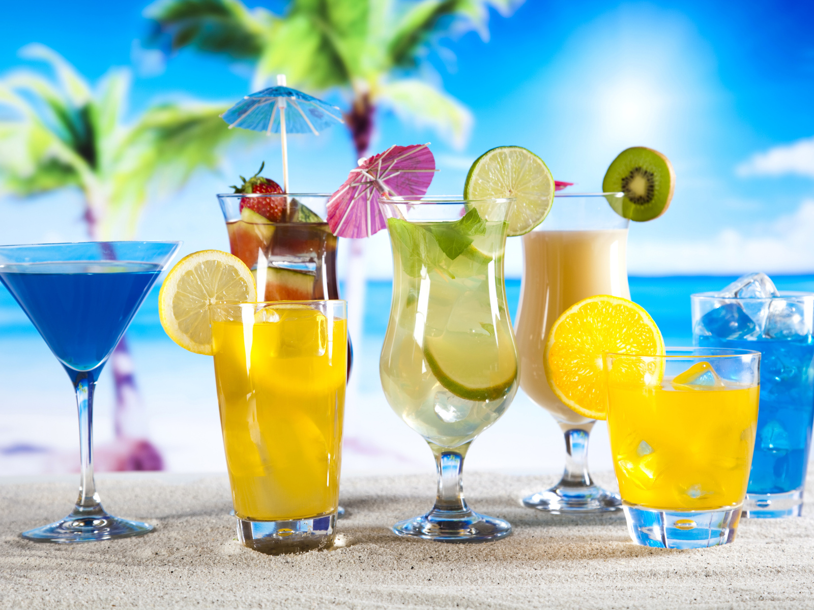 Бокалы с тропическими коктейлями на песке на пляже