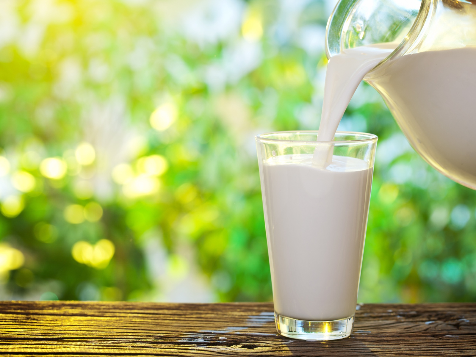 Молоко наливают в стеклянный стакан на столе