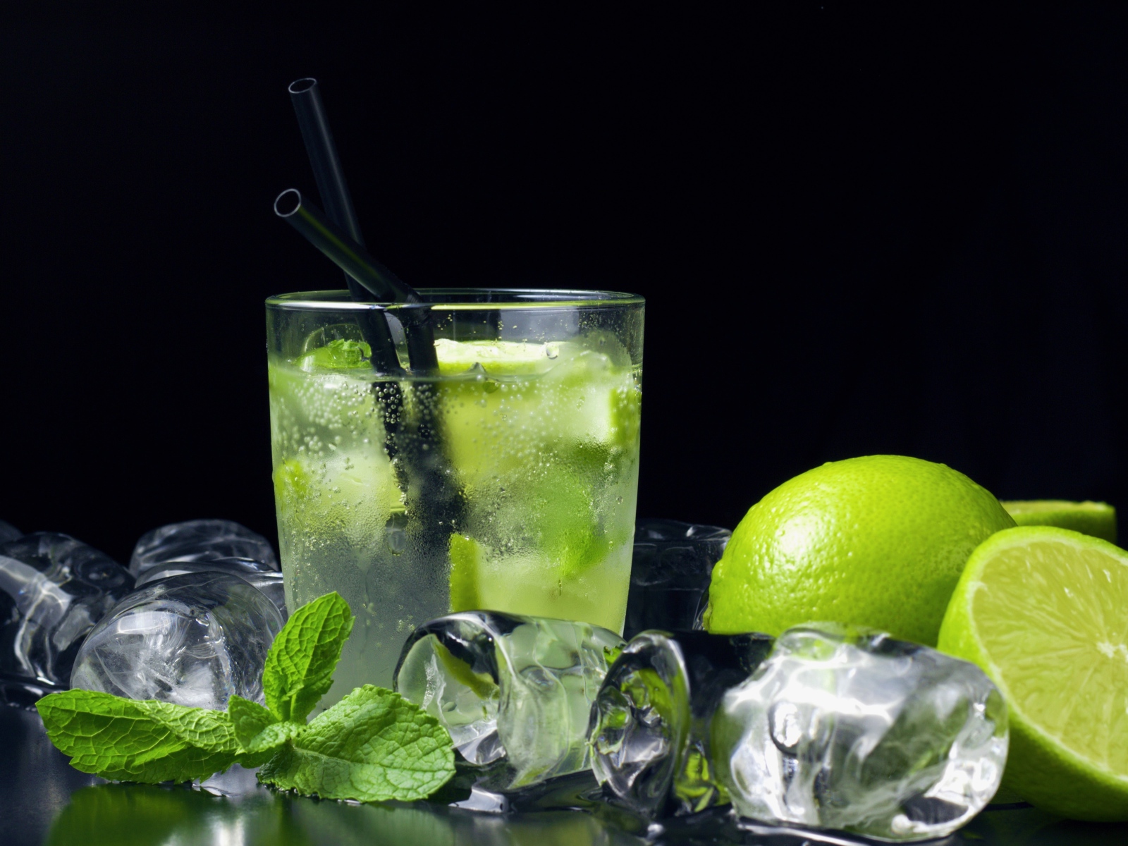 Коктейль мохито на черном фоне с лаймом и кубиками льда