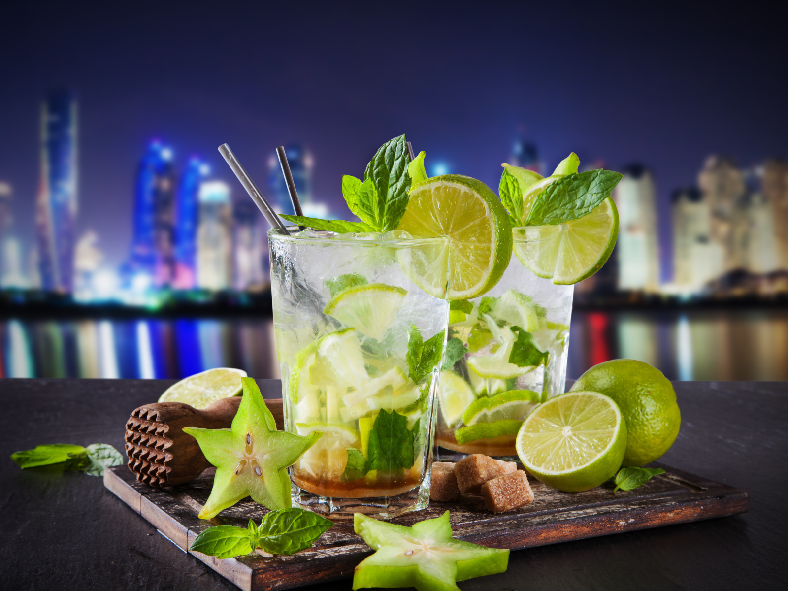 Коктейль мохито с лаймом и карамболью на фоне города