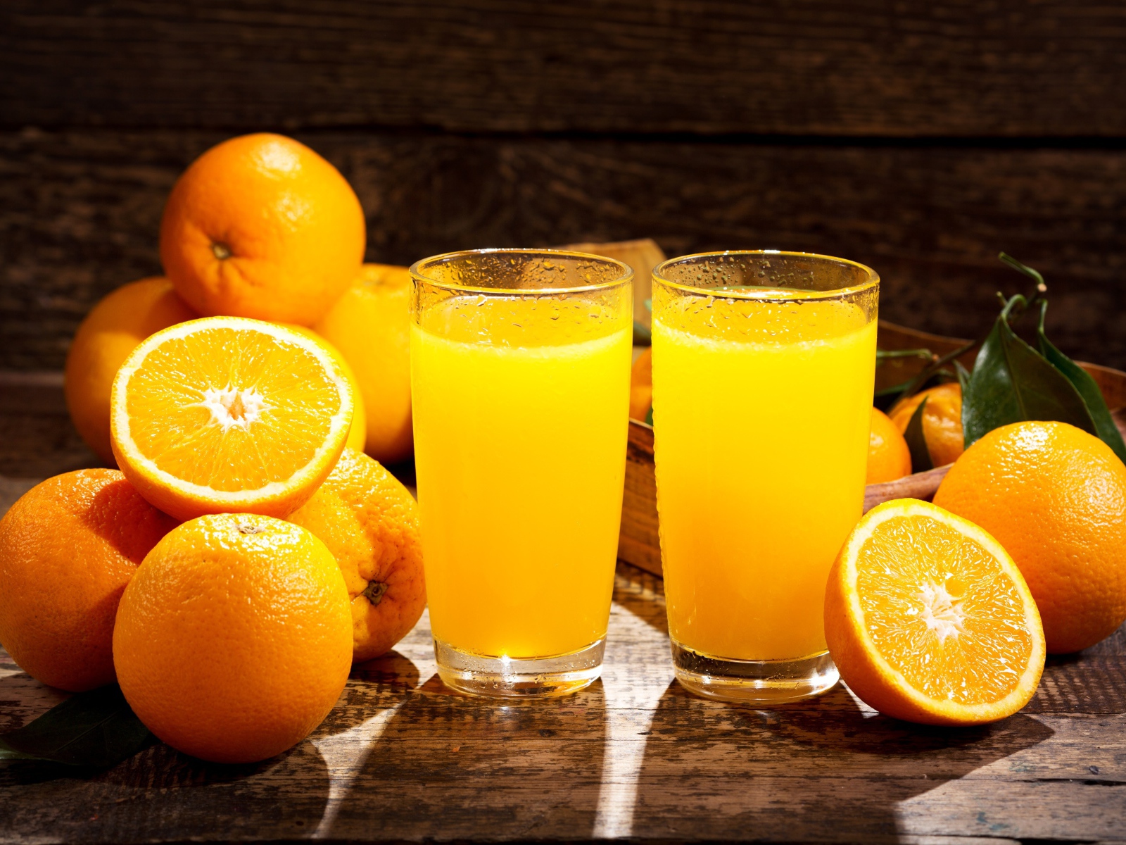 Два стакана свежего апельсинового сока на столе с фруктами