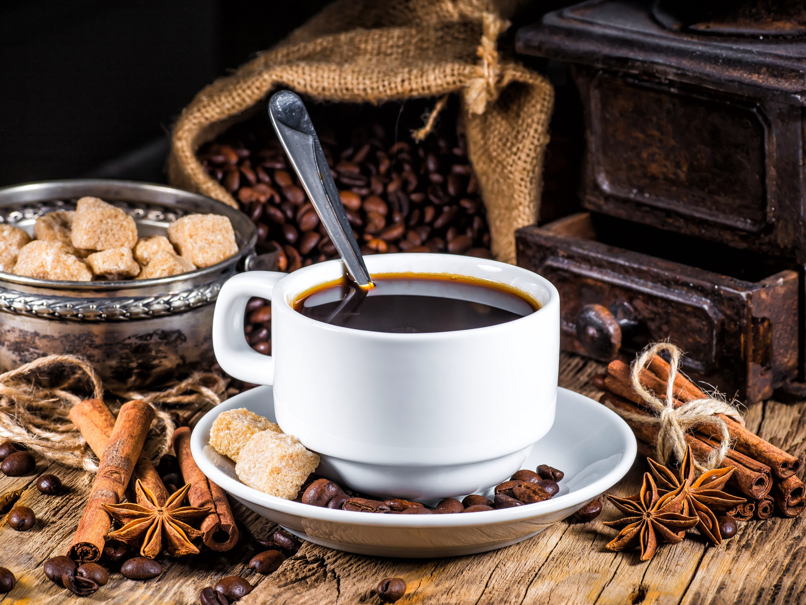 Белая чашка кофе на столе с сахаром, корицей и бадьяном 
