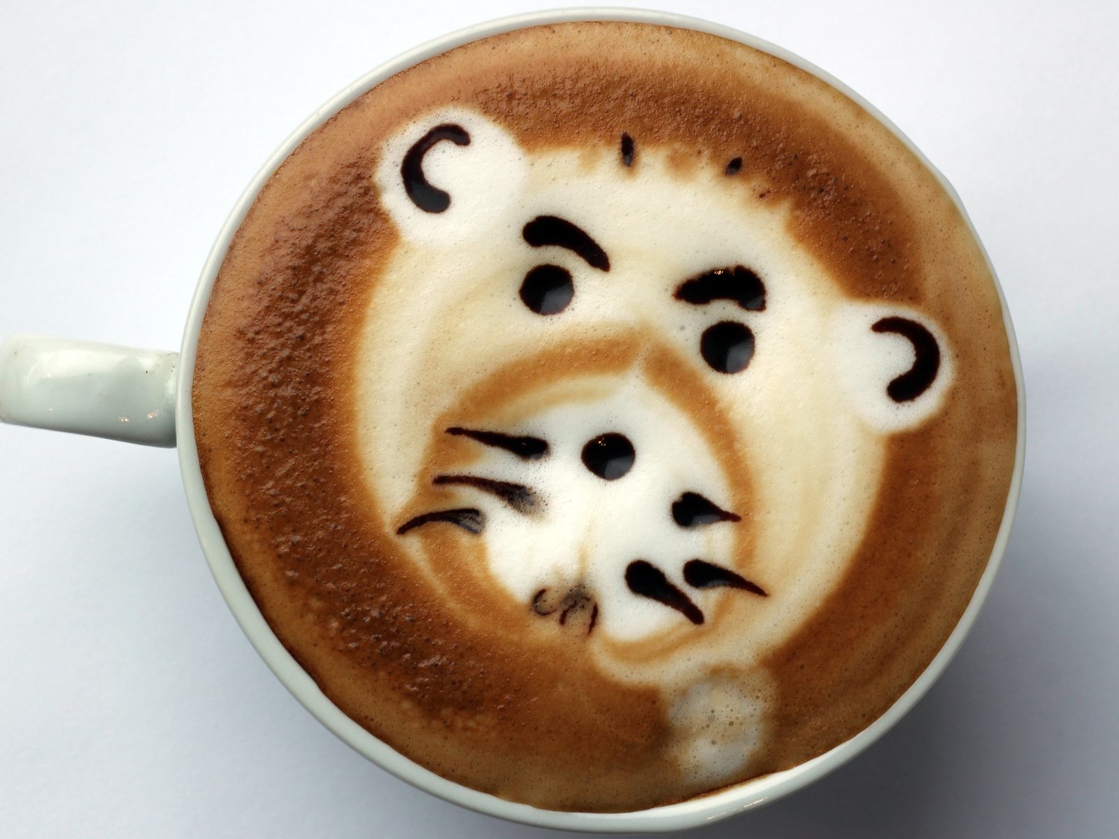 Белая чашка кофе с забавным рисунком на пене