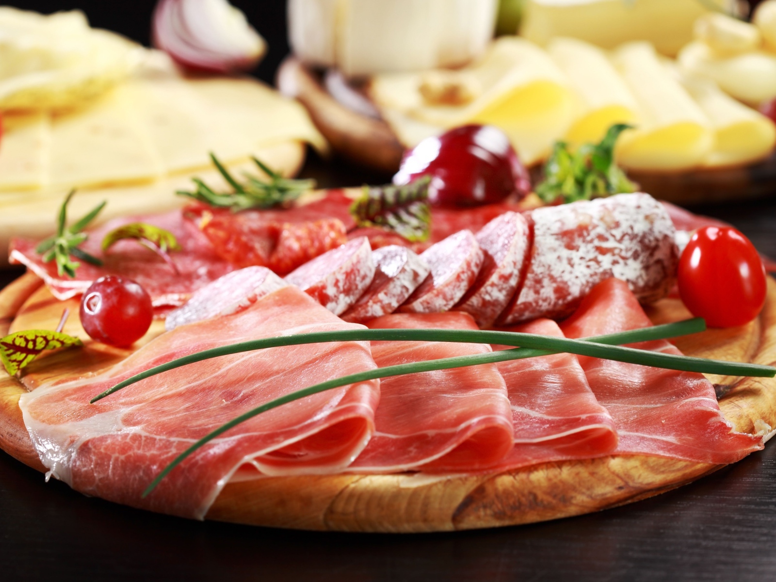 Аппетитная мясная нарезка на деревянной доске с зеленым луком