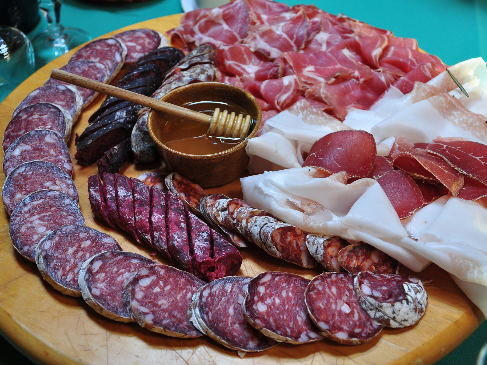 Аппетитная мясная нарезка на разделочной доске с медом