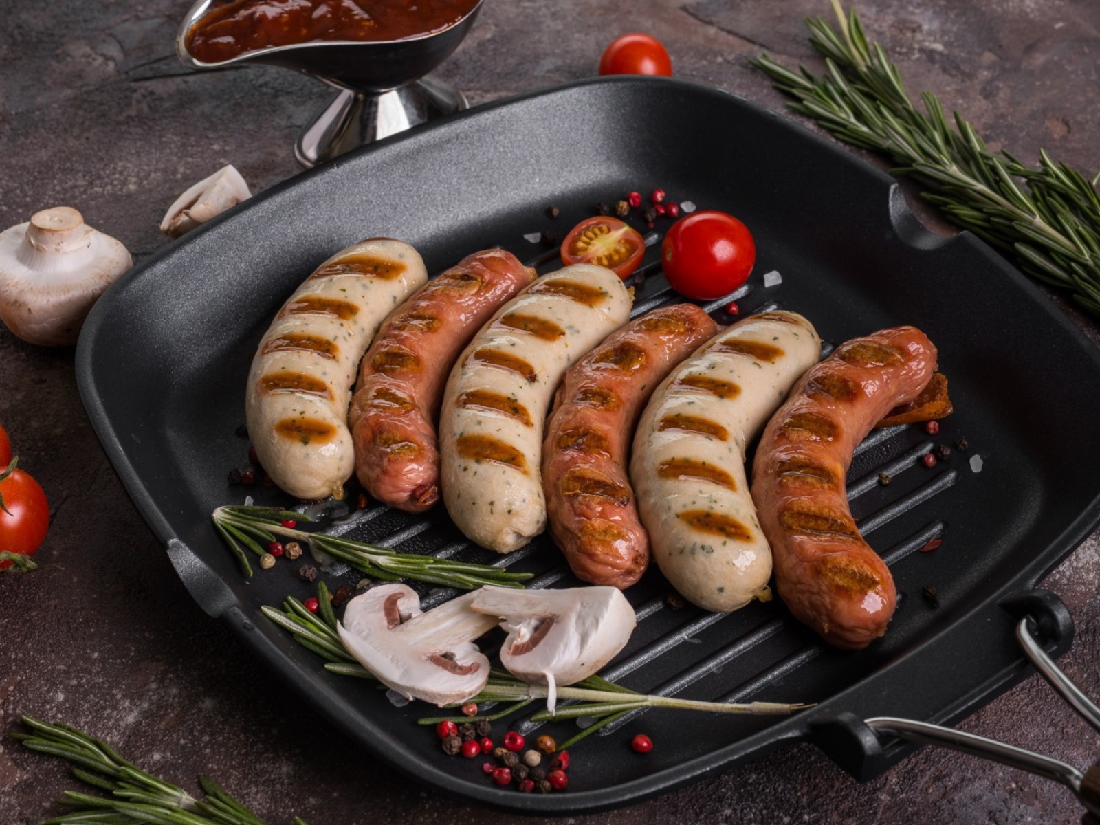 Колбаски гриль на столе с овощами 