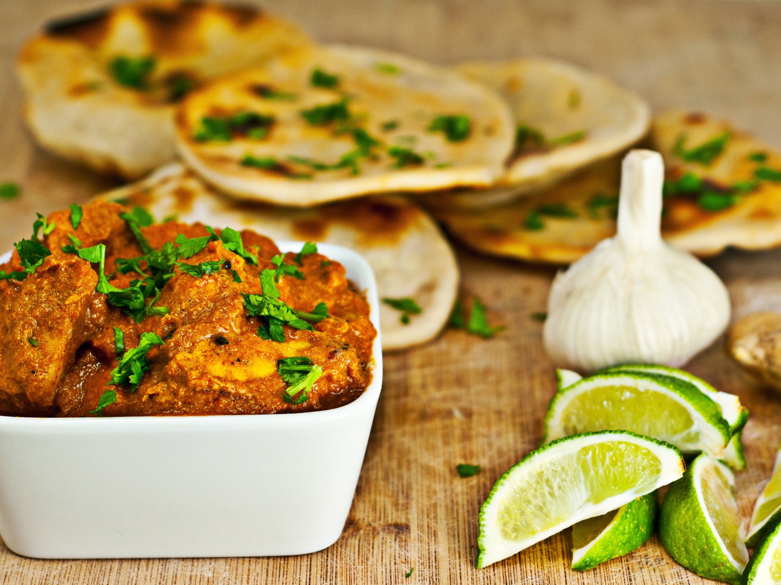 Мясное блюдо на столе с лепешками, кусочками лайма и чесноком