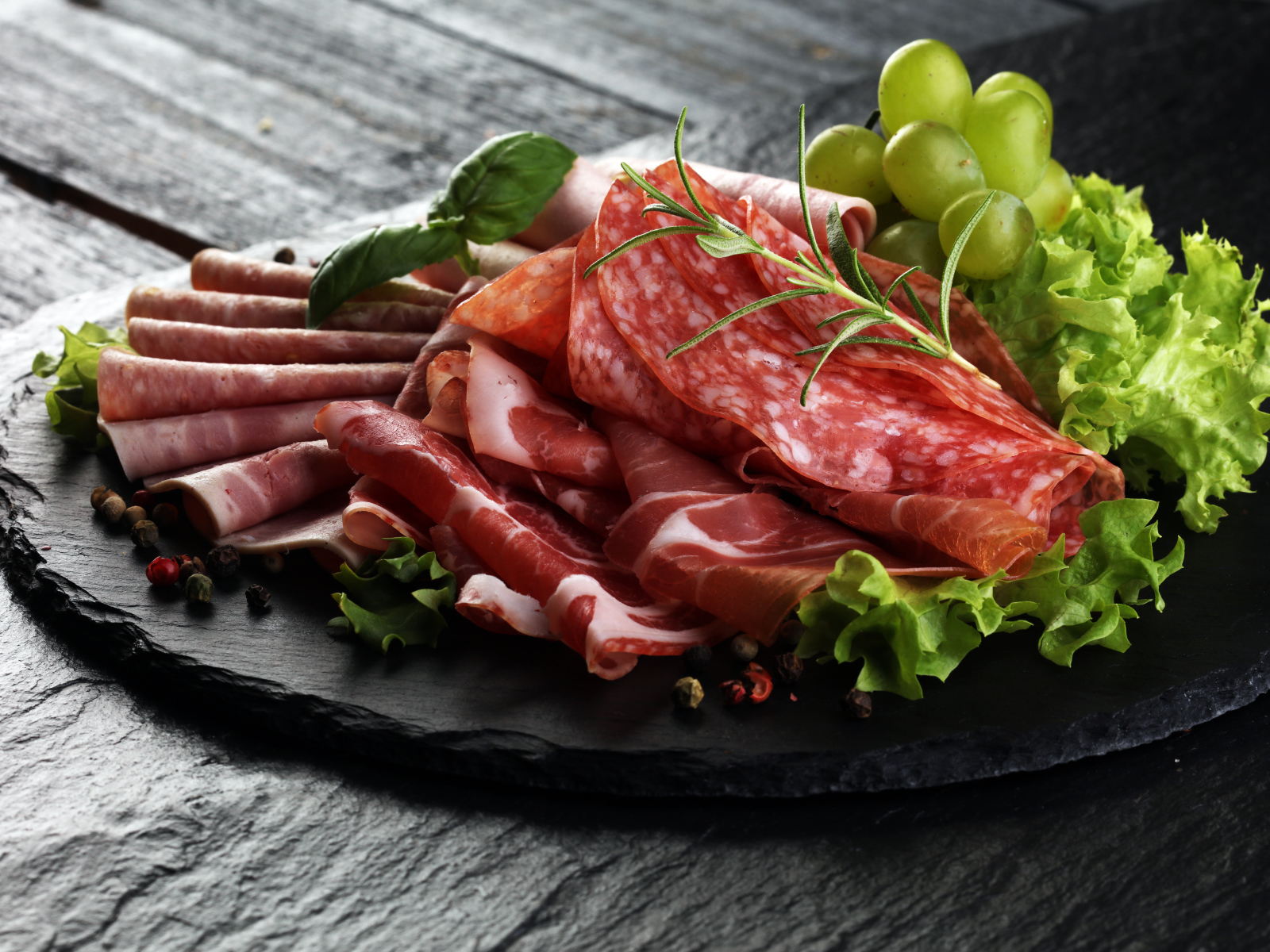 Мясная нарезка с листьями салата и белым виноградом 