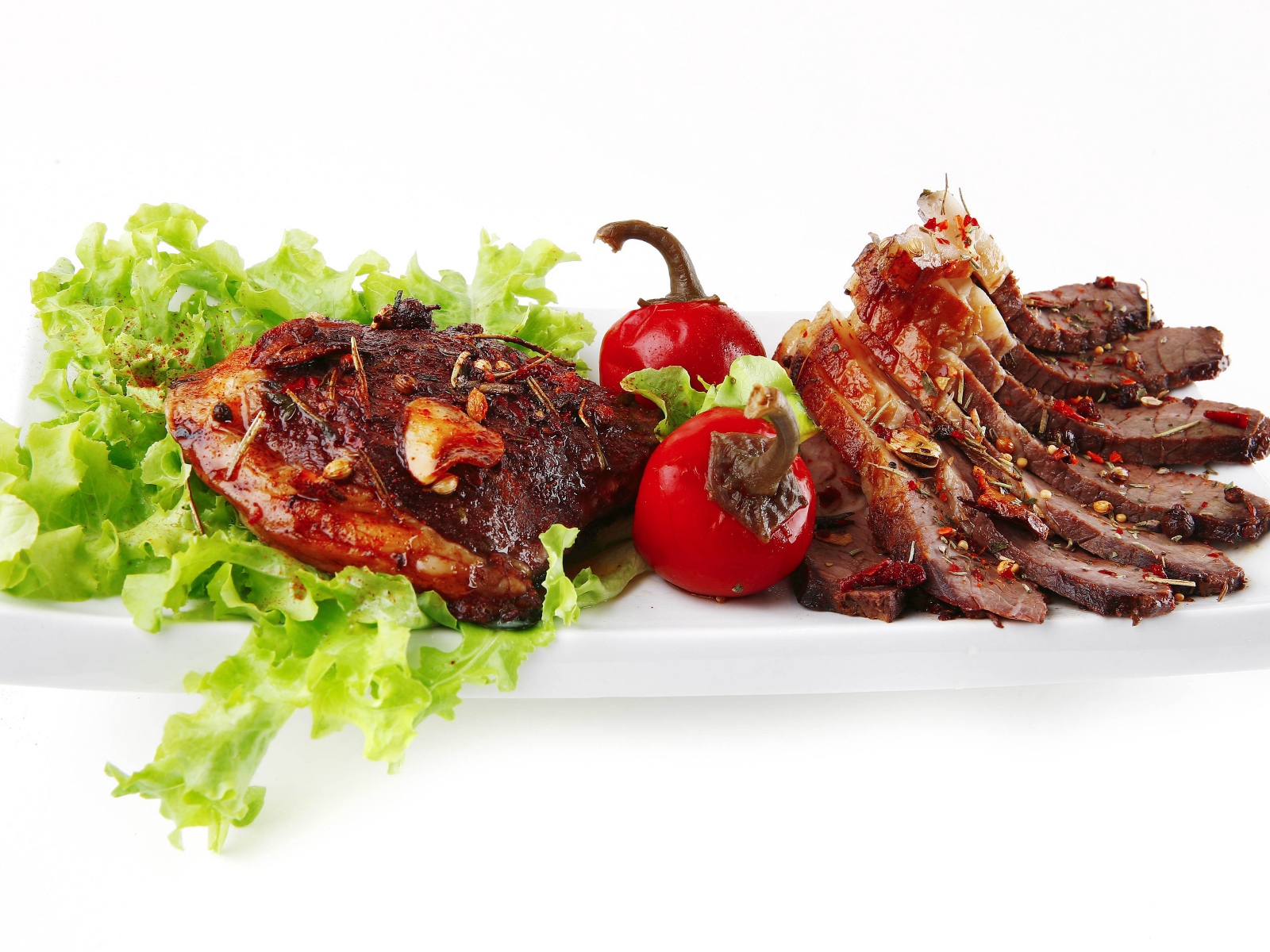 Мясо с листьями салата и красным перцем на белом фоне