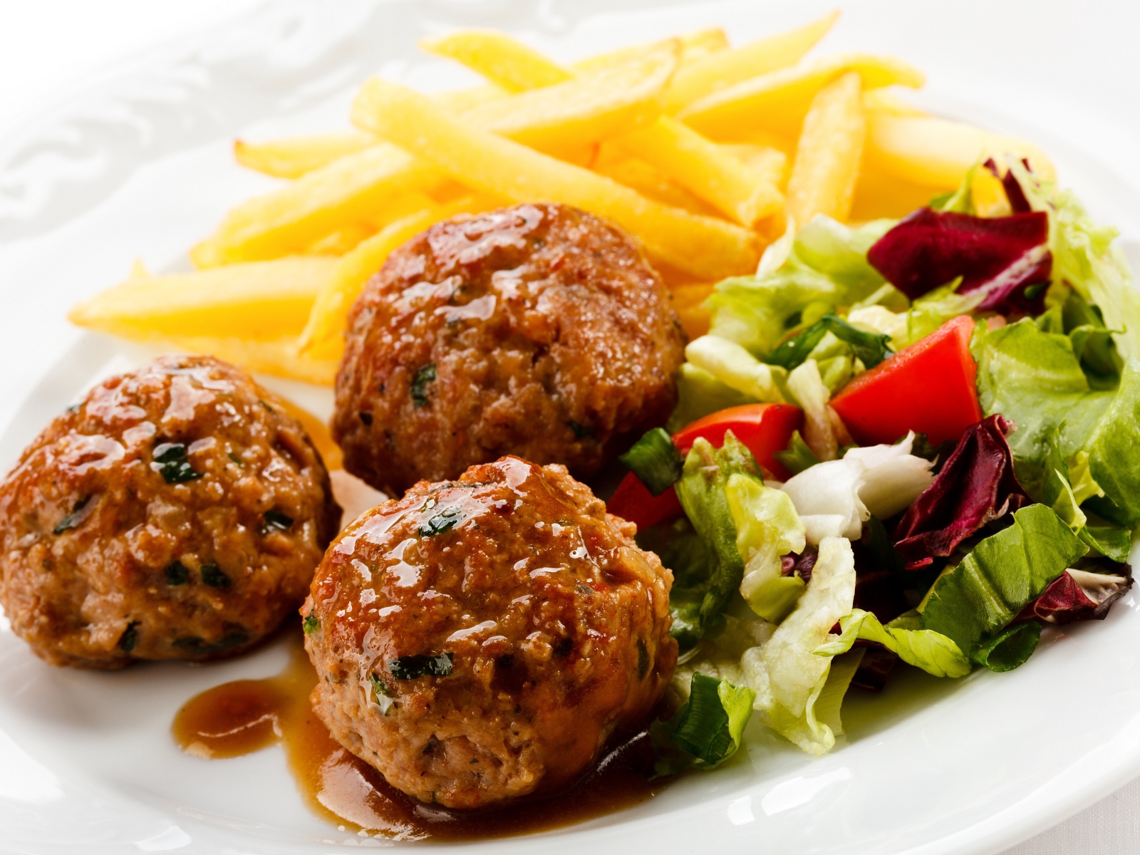 Тефтели с картофелем фри и салатом на белой тарелке 