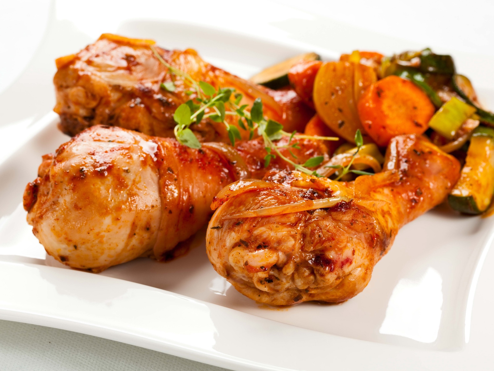 Жареные куриные ножки с овощами на белом фоне