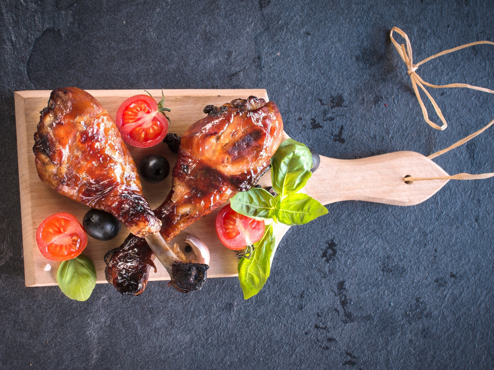 Две зажаренных куриных ножки с овощами на разделочной доске