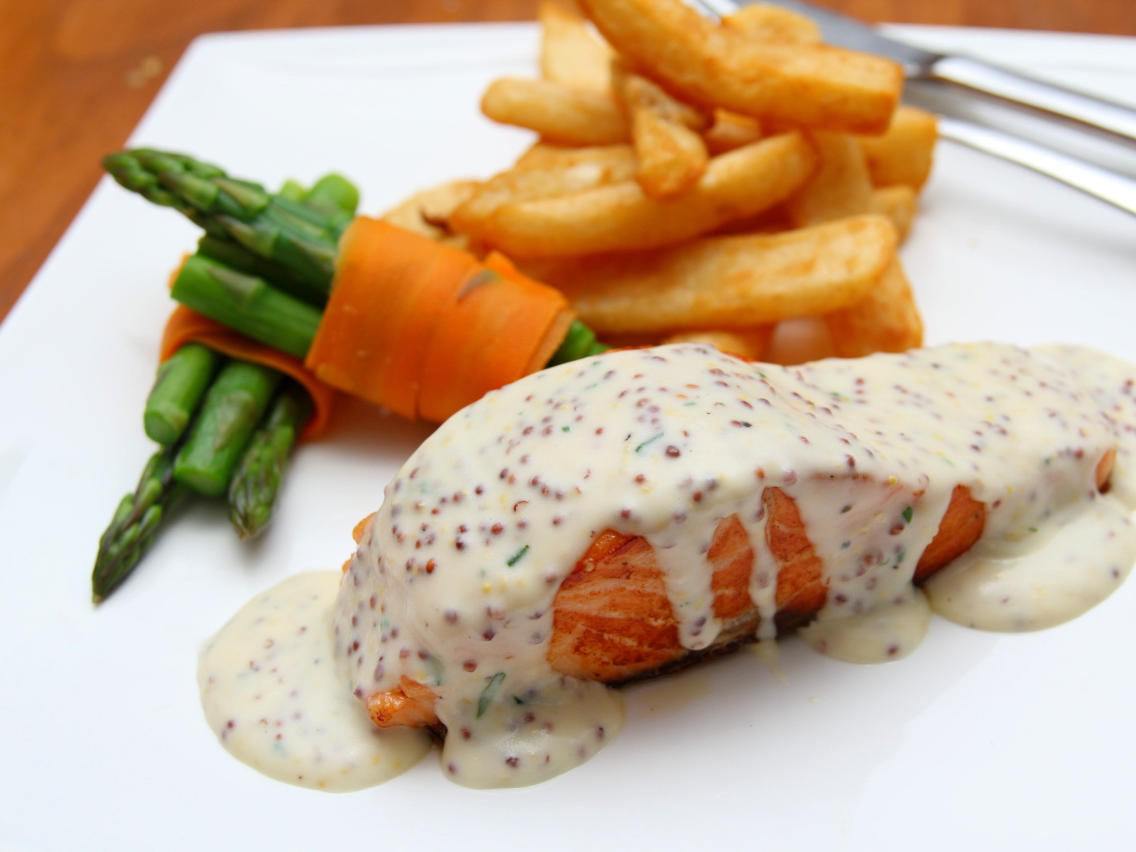 Кусок жареной красной рыбы с соусом на тарелке с картофелем фри 