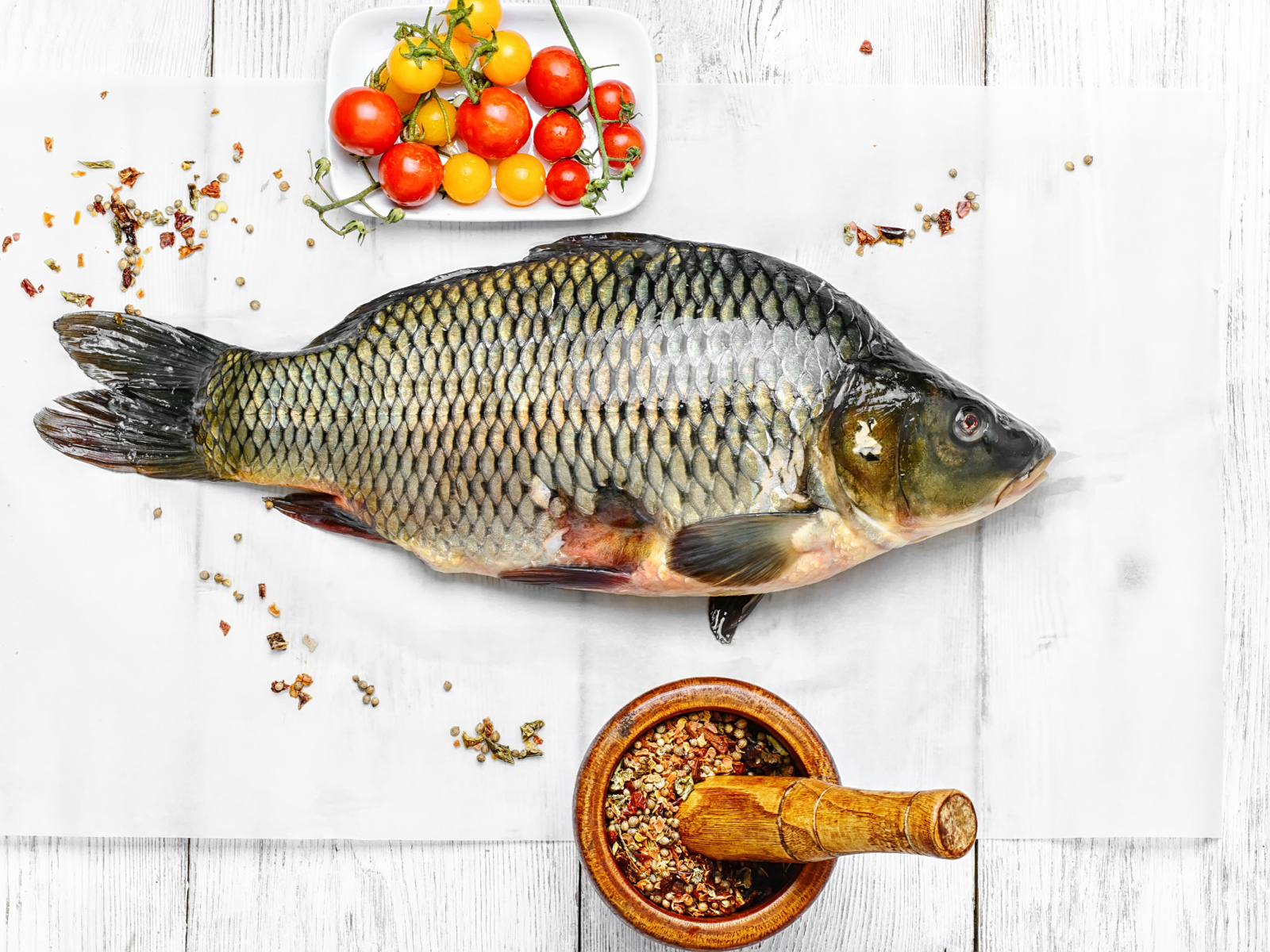 Свежий карась на столе со специями и помидорами