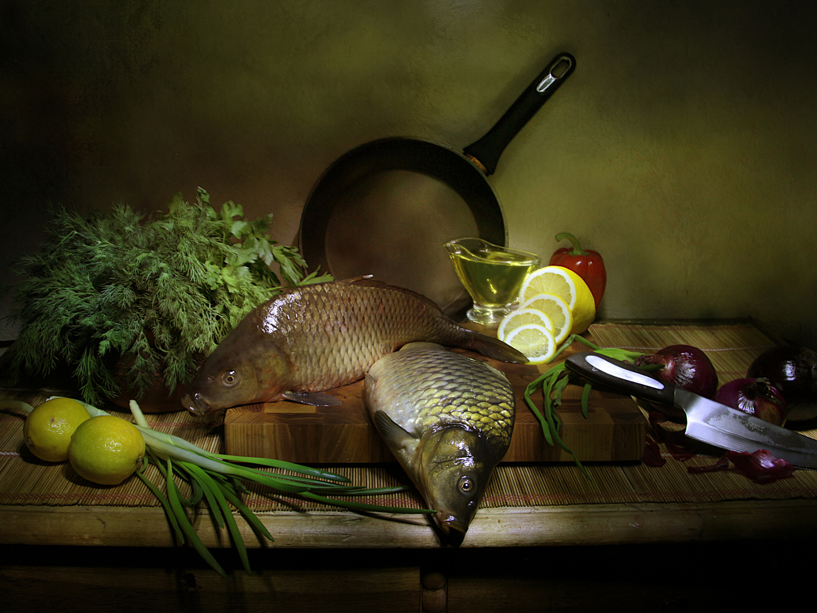 Сырая рыба на столе с зеленью, лимонами и луком 