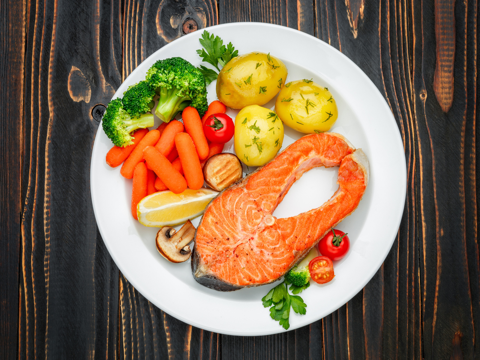 Красная рыба с овощами на белой тарелке на столе