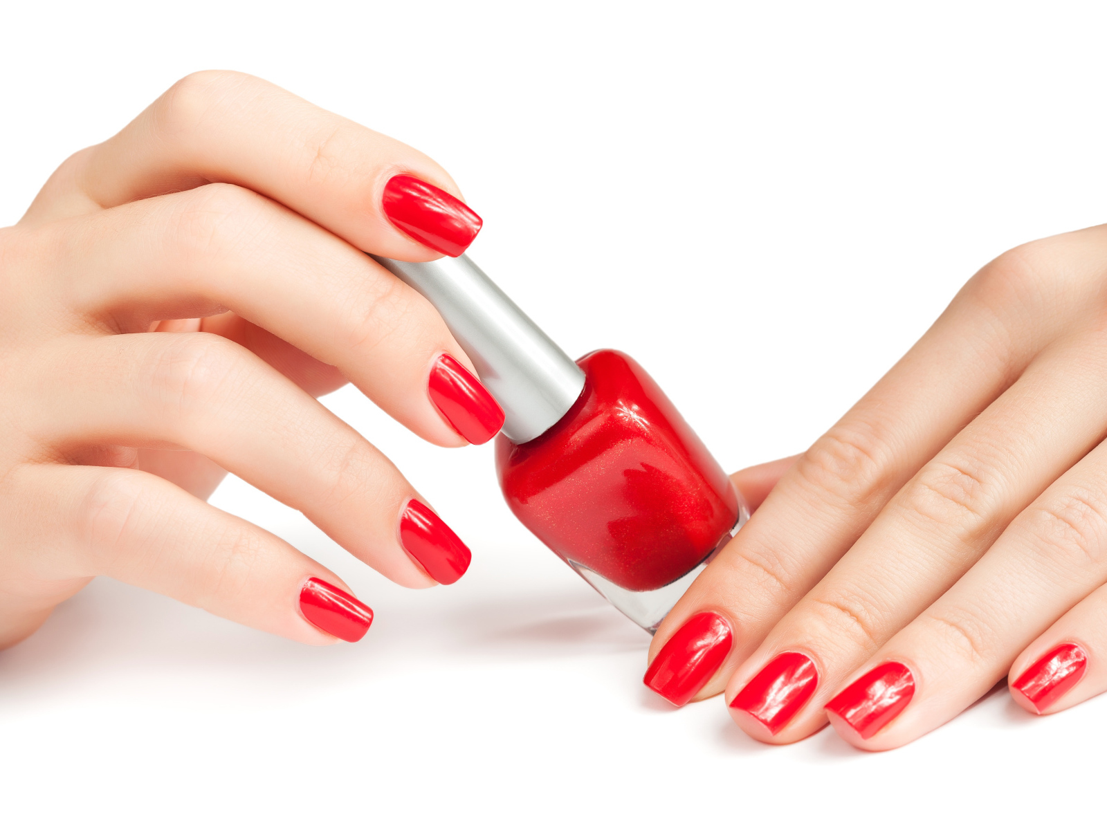 Женские руки с красным маникюром и лаком на белом фоне